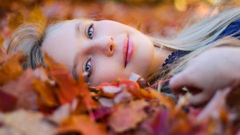 Chica recostada en hojas de otoño